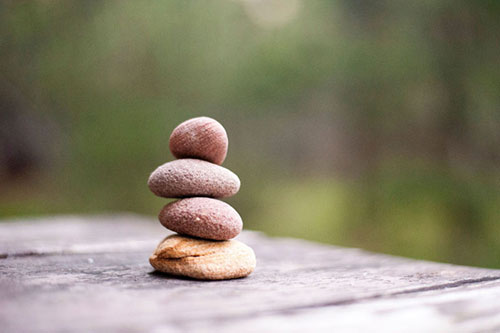 Four rounded stones on slate with a green background in nature.