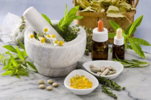 A collection of herbal medicines - a mortar and pestle, some calendula and other fresh herbs in the mortar, a couple of tinctures, and some herbal supplements shown as pills in a small bowl.