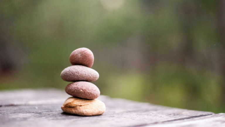 Four healing stones on a stone ledge with green nature in the background